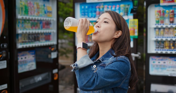 woman drinking tea from a vending machine