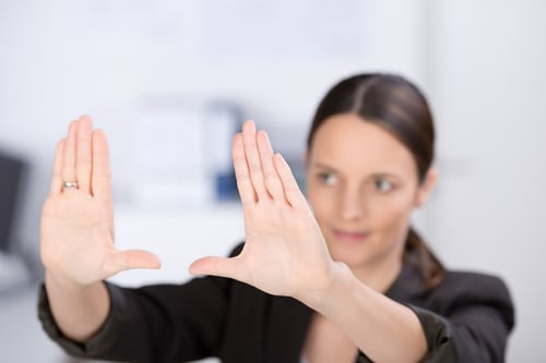 Mid adult businesswoman making hand frame in office, focus hands.jpeg